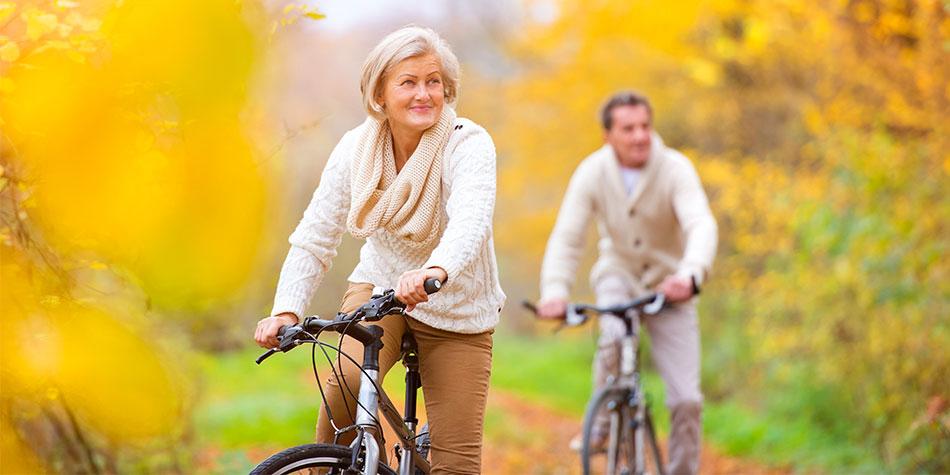 Active seniors riding bikes in autumn nature having a romantic time.