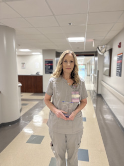 Woman stands in hallway holding plaque, smiling