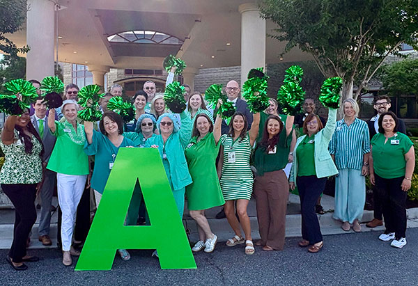 Group of people standing and holding a letter 'A' sign